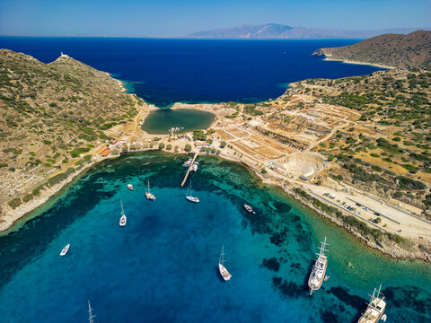 Aerial view of turquoise waters embracing ancient ruins and anchored sailboats, creating a stunning contrast of history and nature, Knidos, Mugla, T&Atilde;&frac14;rkiye.