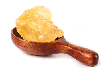 Large chunks of ancient yellow rock sugar from sugar cane displayed in a wooden scoop on a white background