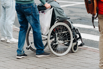 Obraz premium person accompanies disabled person in wheelchair in moving around city