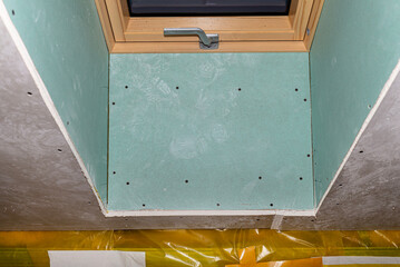 Roof window covered with blue plaster, visible vapor-permeable foil.
