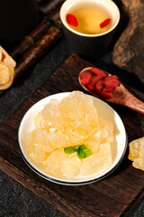 Handmade large grain yellow rock candy served with herbal tea and goji berries on a wooden tray