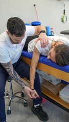 Obraz premium Physiotherapist helps a young woman perform shoulder stretching exercises for rehabilitation