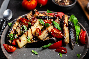 Appetizing salad of eggplants, tomatoes and basil in a black plate