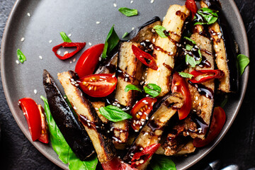 Appetizing salad of eggplants, tomatoes and basil in a black plate