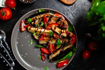 Appetizing salad of eggplants, tomatoes and basil in a black plate
