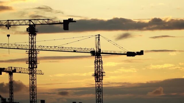 Sunset Over Progress: Construction Cranes Silhouetted Against the Evening Sky