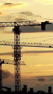 Sunset Over Progress: Construction Cranes Silhouetted Against the Evening Sky