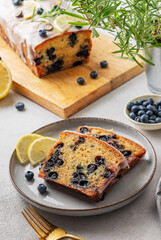 Pieces of homemade blueberry lemon cake on a plate on a light background with fresh berries