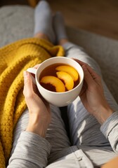 Woman's Hands Holding a Mug of Peach Tea Under Warm Sunlight