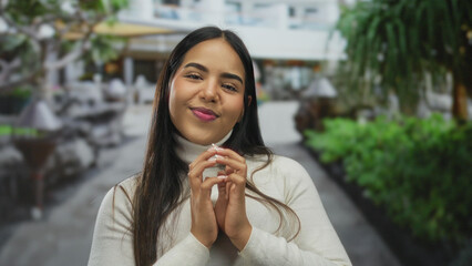 Confident woman hands plotting street latin hispanic young smiling outdoors turtleneck style evokes...