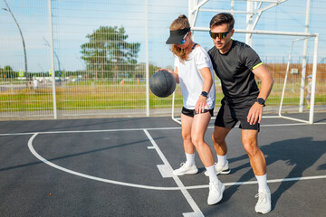 Exciting basketball training with coach and young player in bright court