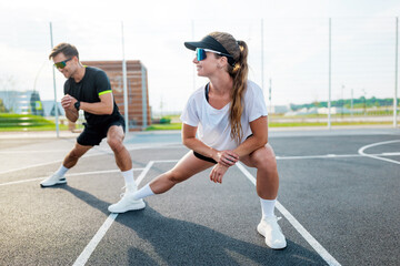 Fitness enthusiasts stretch and warm up on an urban basketball court