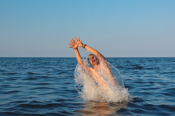 Man jumps out of sea in sunny day
