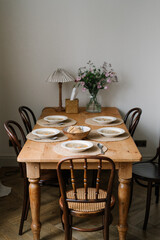 Chicken noodle soups on the wooden vintage dining table, loaf of bread, aesthetic table setting with ceramic crockery	