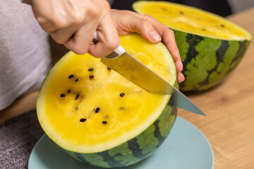 Person cuts watermelon with yellow flesh
