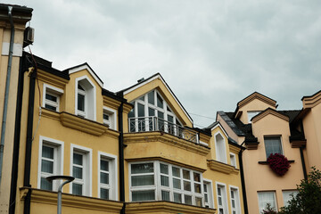Close view of yellow residential building with large windows and decorative architectural details in Sombor, Serbia.