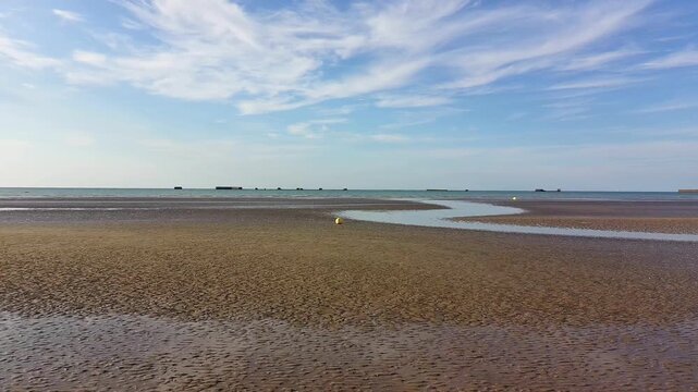Coastal Scene with Buoys and Breakwaters on a Beach at Low Tide - Clear Sky
