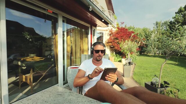 Man reading on patio with headphones