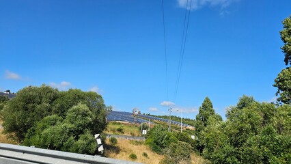 Solar Farm on a Hillside Surrounded by Trees and Power Lines