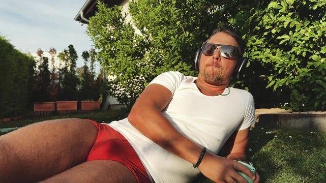 Man lying on grass with headphones at golden hour