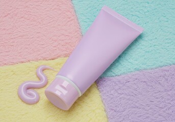 A lilac cream tube with a swirl of cream on a pastel background