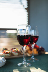 Red wine glasses, bruschettas with tomatoes, salami and basil, bread, Camembert cheese, grapes. Summertime, dating concept. Home party concept.