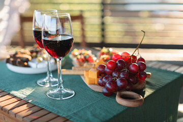 Red wine and delicious gourmet appetizers on a terrace table on a sunny summer day.