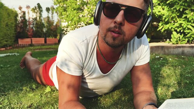 Man relaxing on garden grass with book