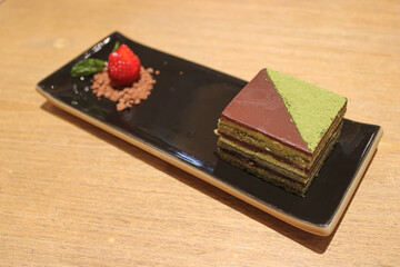 Delicious Matcha and Chocolate Layer Cake Served with a Fresh Strawberry on a Black Plate