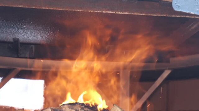 A chef lights a fire with a blowtorch under a large, metal cooking drum before submerging large chunks of seasoned, raw meat into a bubbling brown sauce.