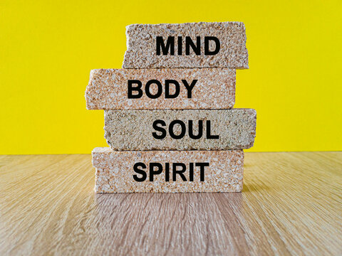 Lifestyle concept mind body soul spirit on brick blocks. Beautiful yellow background, wooden table.