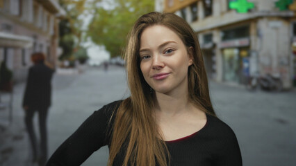Fototapeta premium Woman with subtle smile showing bare neck and looking at camera on city street; confidence empowerment.