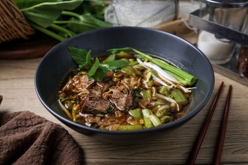 Vegetable noodle soup with stewed pork in black bowl