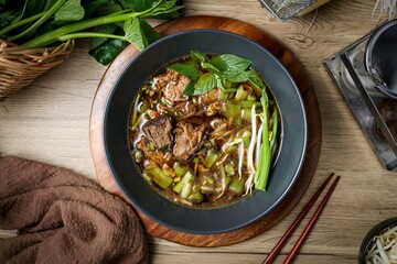 Vegetable noodle soup with stewed pork in black bowl