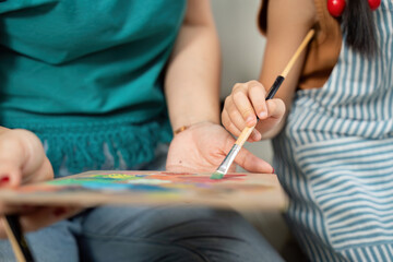Collaborative art. Mother and daughter painting together with vibrant colors.