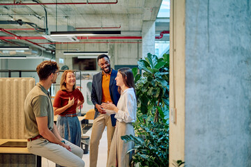 Multicultural businesspeople talking and smiling during a meeting in a modern office with plants