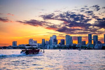 Fototapeta premium A pontoon boat heads across Toronto's Inner Harbour with the city skyline and the sunset in the background shot in mid summer room for text copy space