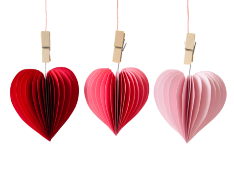 Three colorful paper heart decorations hanging from wooden clothespins isolated on transparent background