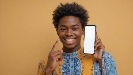 A young man with curly hair smiling and holding a smartphone with a blank screen in his hand