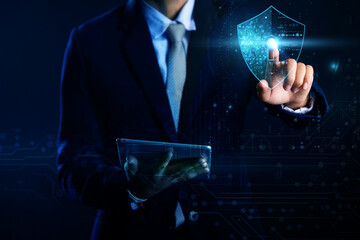businessman pressing virtual button. A businessman in a dark suit interacts with a holographic security shield displayed over a tablet.