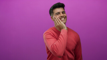 Fototapeta premium Young man in a red shirt smiling against a vibrant pink background, capturing a cheerful and friendly mood with an expressive pose.