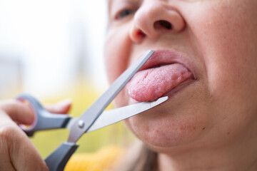 Close up of woman cutting tongue with scissors humorous concept silence censorship sarcasm stop...
