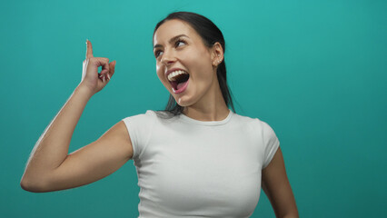 Woman smiling and pointing upward against a vibrant green background, expressing happiness and confidence.
