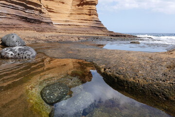 Bunte Felsen mit Steinen und Pfützen an der Küste am Callao de la Cochina in Costa del Silencio...