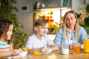Happy family sister and brother have breakfast with cereal and milk in a kitchen at home