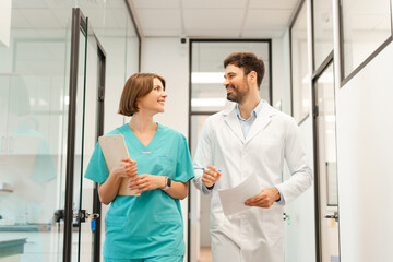 Doctor and nurse discussing walking in hospital corridor