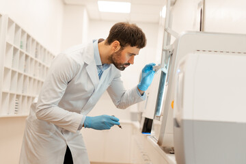 Scientist placing sample in analyzer for chemical analysis in laboratory