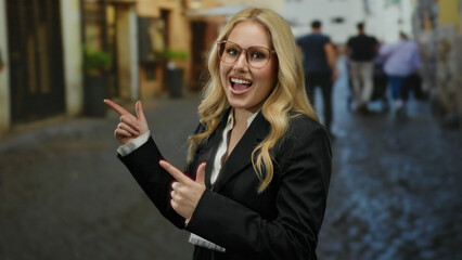 Fototapeta premium Woman smiling and pointing on a cobblestone street in a city with blonde hair and wearing glasses outdoors during daylight showcasing urban environment and fashion.
