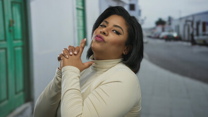 Confident plus-size hispanic woman in urban street setting makes playful finger guns gesture with a confident expression.