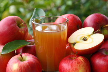 Fresh apple juice in a glass and fruits on a white table outdoors, close up
